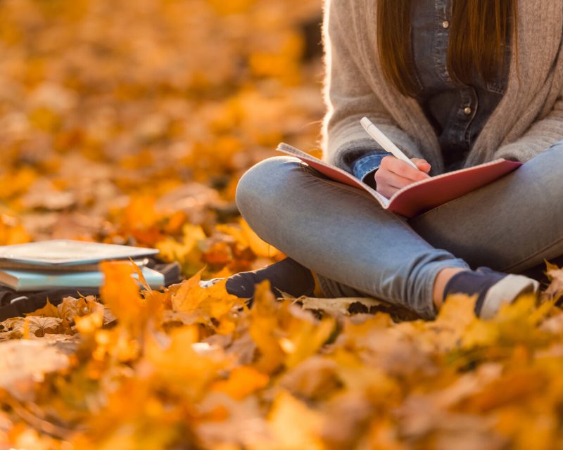Young happy girl students while walking autumn park